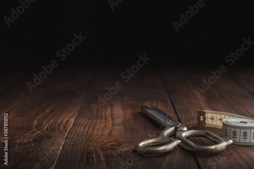Fotografía Sewing items - tailoring scissors and measuring tape on dark wooden table