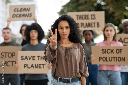 Young woman showing peace gesture, leading group of demonstrators photo