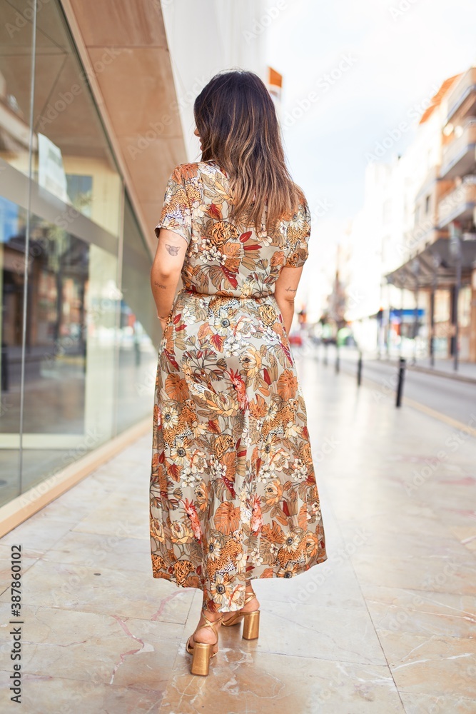 Beautiful young woman wearing fashionable clothes walking down the street