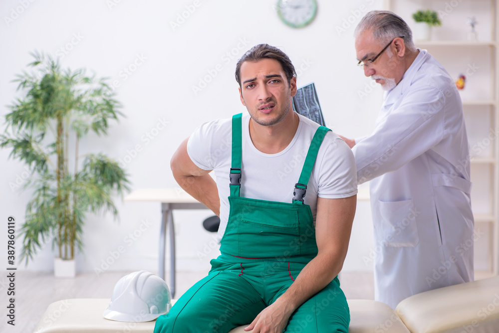 Fototapeta premium Young male contractor visiting old doctor