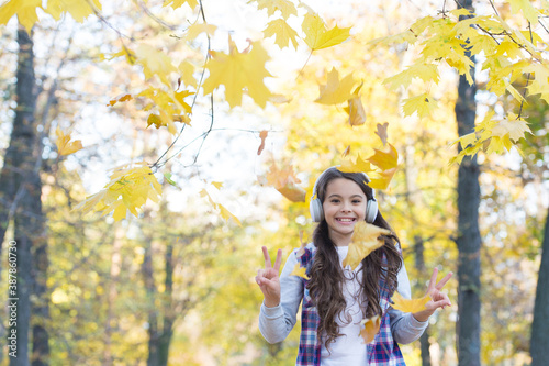 happy girl in casual style spend time in autumn forest with maple leaves enjoying good weather while listening music in headphones, happy childhood