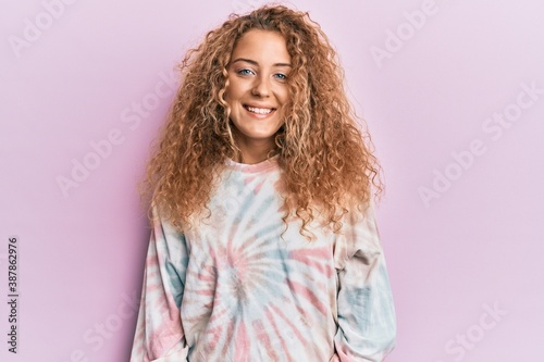 Beautiful caucasian teenager girl wearing casual tie dye sweatshirt looking positive and happy standing and smiling with a confident smile showing teeth