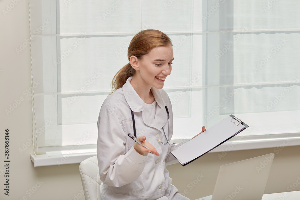 A young female doctor is holding a clipboard, interviewing a patient and smiling. White background. Medical worker. A young female doctor is holding a clipboard, interviewing a patient and smiling. White background. Medical worker.