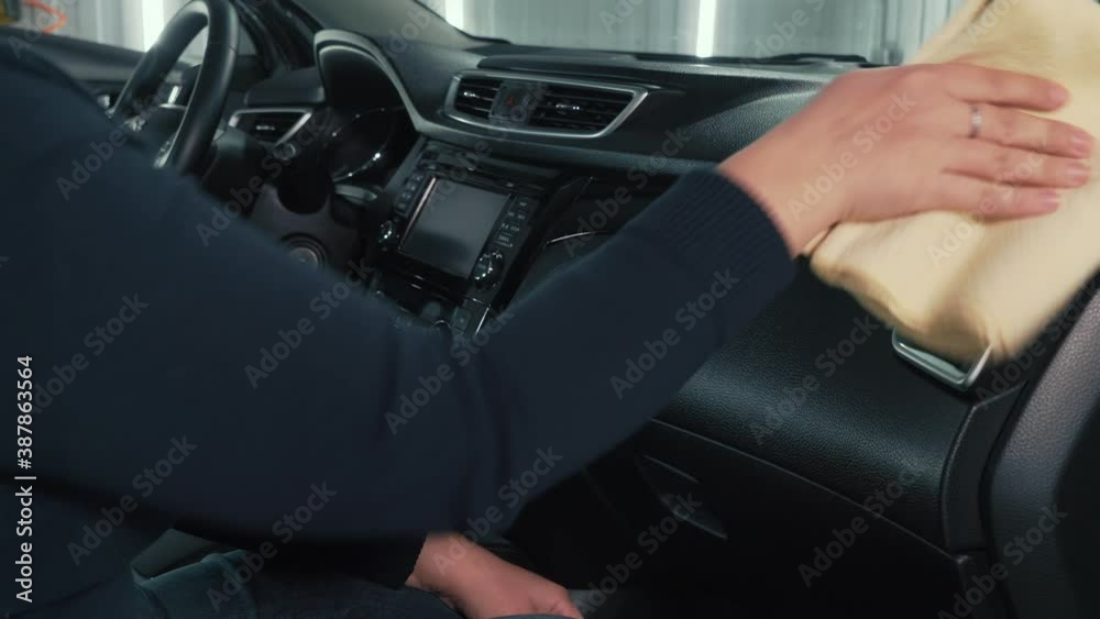 Woman auto cleaner puffs spray on microfiber and wipes dashboard and plastic of car interior inside. Woman auto cleaner puffs spray on microfiber and wipes dashboard and plastic of car interior inside.