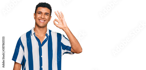 Young arab man wearing casual clothes smiling positive doing ok sign with hand and fingers. successful expression.