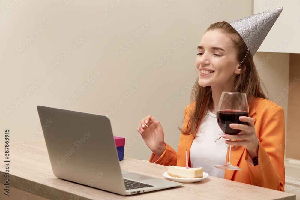 Young beautiful woman sitting at home, looking at the laptop screen with a glass of wine in her hand. Holiday online during the quarantine. Young beautiful woman sitting at home, looking at the laptop screen with a glass of wine in her hand. Holiday online during the quarantine.