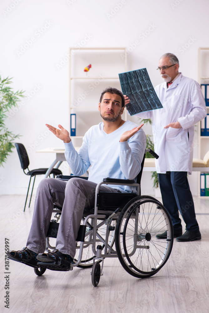 Young man in wheel-chair and old doctor radiologist Young man in wheel-chair and old doctor radiologist