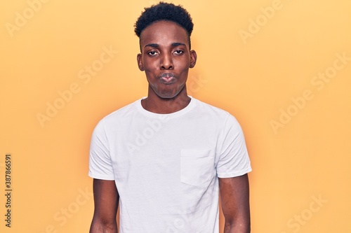 Young african american man wearing casual clothes puffing cheeks with funny face. mouth inflated with air, crazy expression. © Krakenimages.com