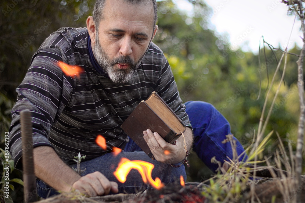  man with a book in a natural environment with flames present