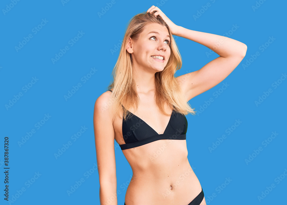 Fototapeta premium Young beautiful blonde woman wearing bikini smiling confident touching hair with hand up gesture, posing attractive and fashionable