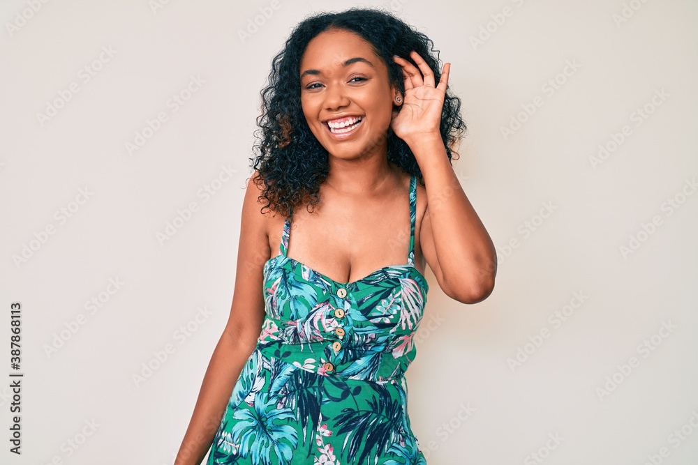 Young african american woman wearing casual clothes smiling with hand over ear listening an hearing to rumor or gossip. deafness concept. Young african american woman wearing casual clothes smiling with hand over ear listening an hearing to rumor or gossip. deafness concept.
