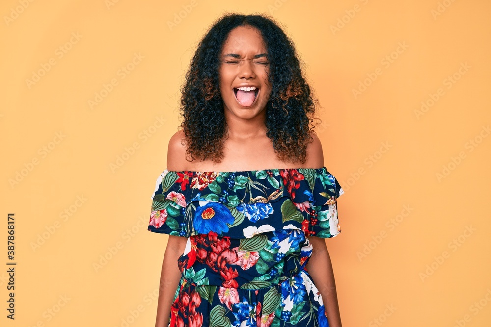 Young african american woman wearing casual clothes sticking tongue out happy with funny expression. emotion concept. Young african american woman wearing casual clothes sticking tongue out happy with funny expression. emotion concept.