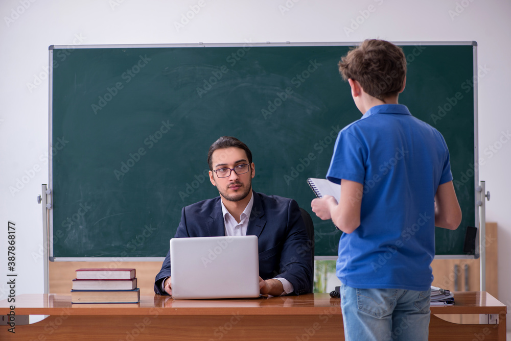 Young male teacher and schoolboy in the classroom - obrazy, fototapety, plakaty 
