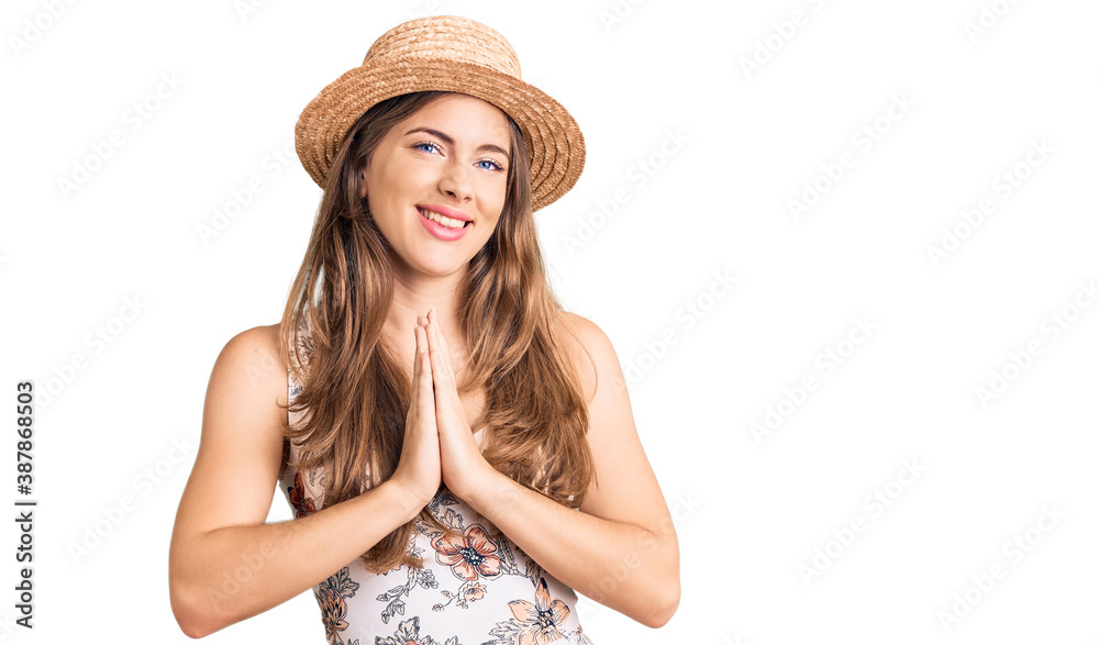 Beautiful caucasian young woman wearing summer hat praying with hands together asking for forgiveness smiling confident. Beautiful caucasian young woman wearing summer hat praying with hands together asking for forgiveness smiling confident.