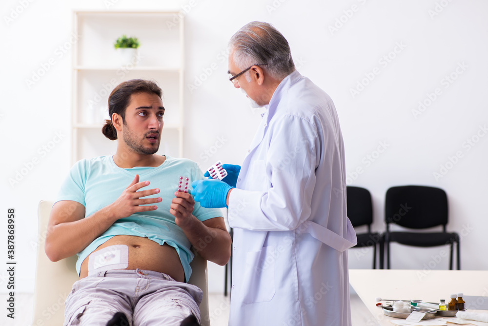 Injured young man visiting experienced male doctor