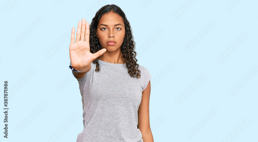 Young african american girl wearing casual clothes doing stop sing with palm of the hand. warning expression with negative and serious gesture on the face. Young african american girl wearing casual clothes doing stop sing with palm of the hand. warning expression with negative and serious gesture on the face.