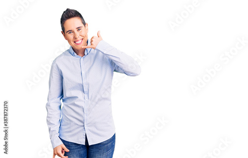 Young woman with short hair wearing business clothes smiling doing phone gesture with hand and fingers like talking on the telephone. communicating concepts.