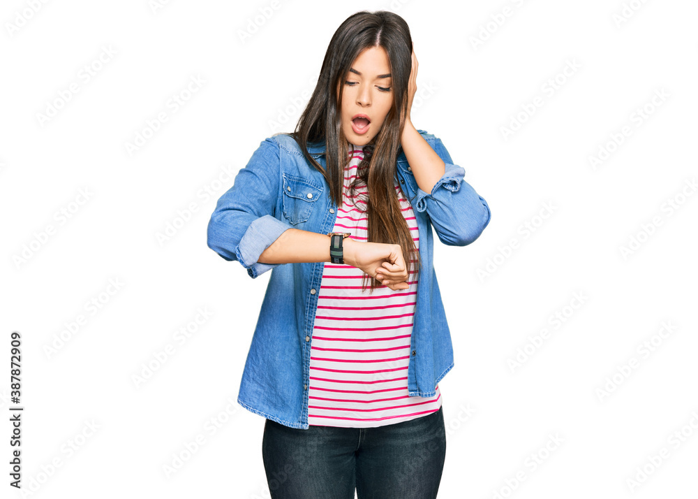 Young brunette woman wearing casual clothes looking at the watch time worried, afraid of getting late Young brunette woman wearing casual clothes looking at the watch time worried, afraid of getting late