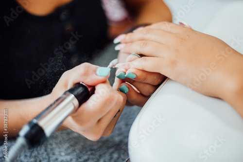 Young woman getting a beautiful manicure in the salon. The process of making nails.