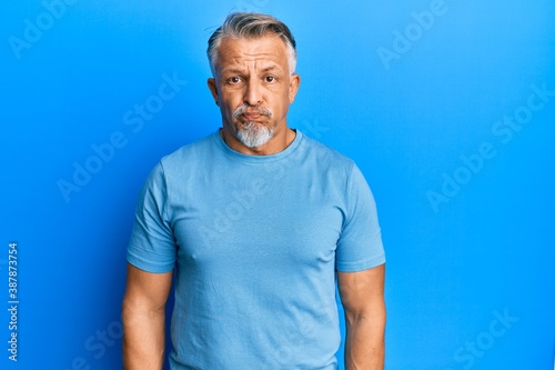 Middle age grey-haired man wearing casual clothes puffing cheeks with funny face. mouth inflated with air, crazy expression. © Krakenimages.com