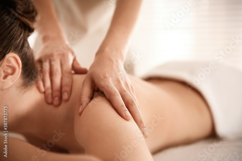 Young woman receiving shoulder massage in spa salon, closeup
