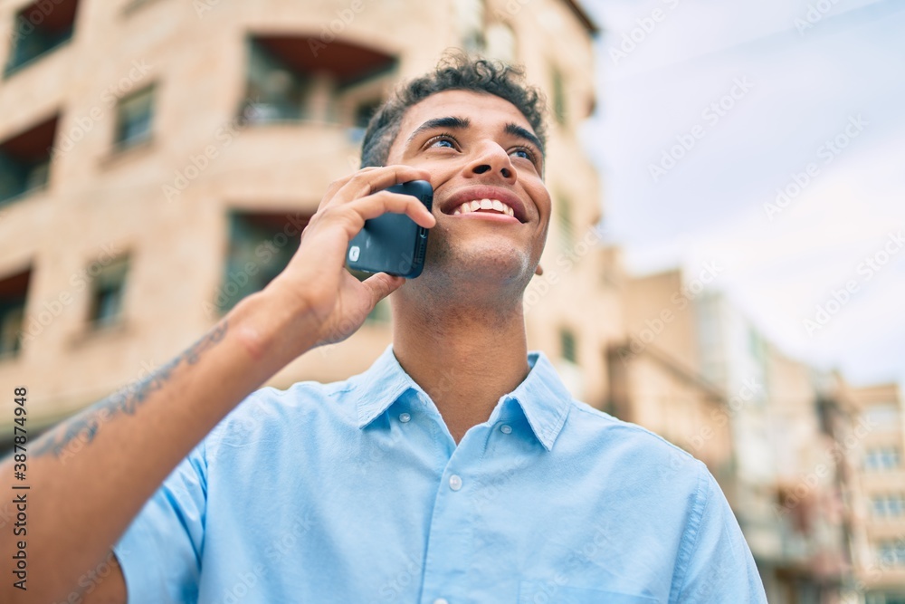 Young latin man smiling happy talking on the smartphone walking at the city. Young latin man smiling happy talking on the smartphone walking at the city.