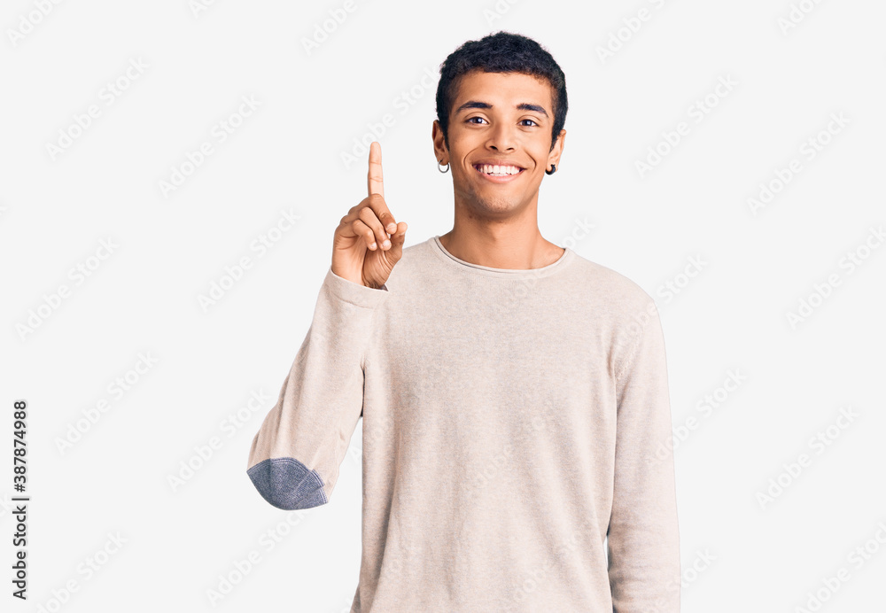 Young african amercian man wearing casual clothes showing and pointing up with finger number one while smiling confident and happy. Young african amercian man wearing casual clothes showing and pointing up with finger number one while smiling confident and happy.