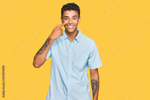 Young handsome african american man wearing casual clothes pointing with hand finger to face and nose  smiling cheerful. beauty concept