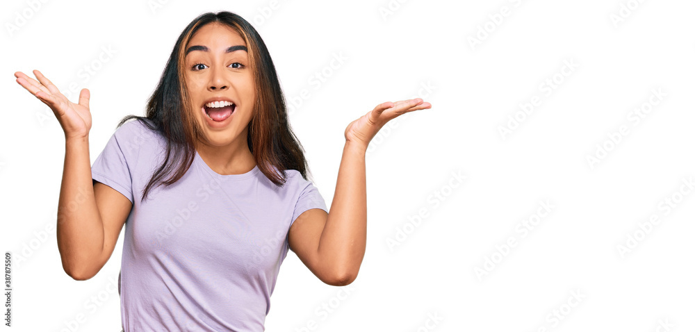 Young latin woman wearing casual clothes celebrating crazy and amazed for success with arms raised and open eyes screaming excited. winner concept Young latin woman wearing casual clothes celebrating crazy and amazed for success with arms raised and open eyes screaming excited. winner concept
