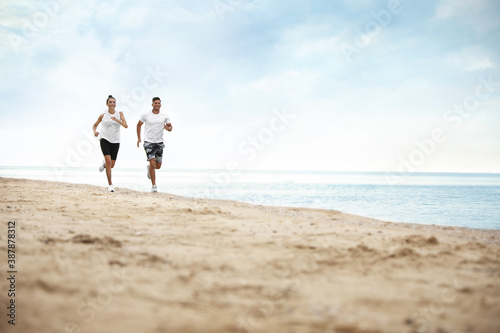 Couple running together on beach  space for text. Body training