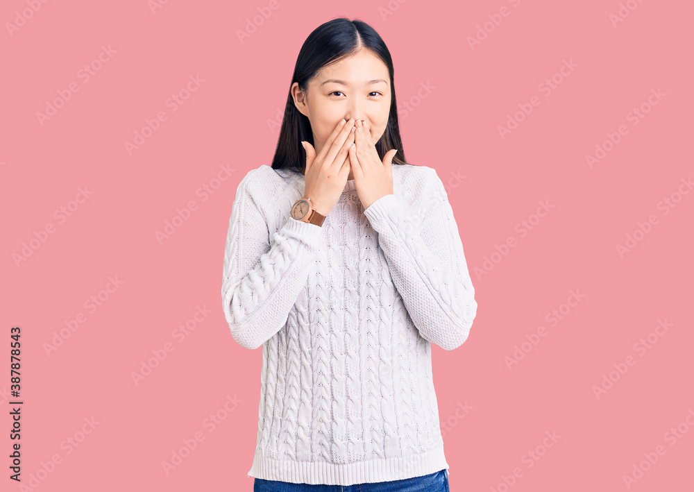 Young beautiful chinese woman wearing casual sweater laughing and embarrassed giggle covering mouth with hands, gossip and scandal concept Young beautiful chinese woman wearing casual sweater laughing and embarrassed giggle covering mouth with hands, gossip and scandal concept