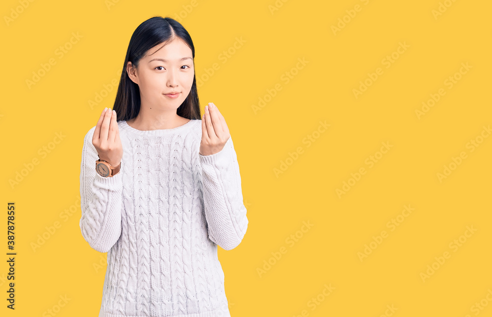 Young beautiful chinese woman wearing casual sweater doing money gesture with hands, asking for salary payment, millionaire business Young beautiful chinese woman wearing casual sweater doing money gesture with hands, asking for salary payment, millionaire business