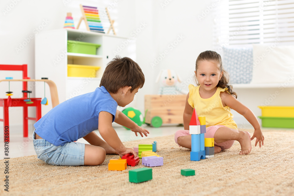 Cute little children playing with colorful blocks on floor indoors. Educational toy Cute little children playing with colorful blocks on floor indoors. Educational toy
