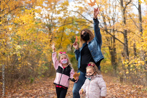 Grandmother with two young granddaughters exploring nature and collecting colorful fall leaves