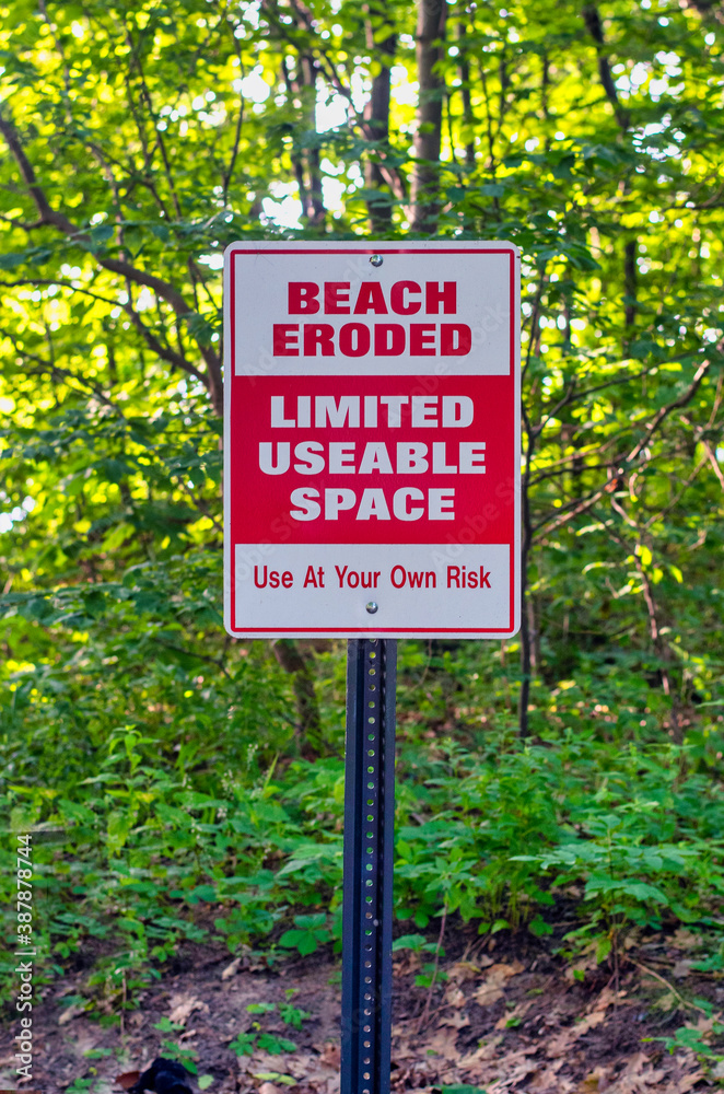 sign on a Michigan breach warns of limited space, as high waves destroyed a lot of beach area in this state