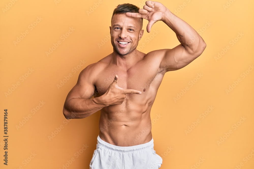 Handsome muscle man standing shirtless smiling making frame with hands and fingers with happy face. creativity and photography concept.