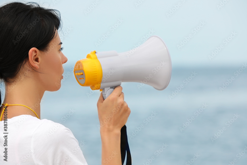 Beautiful female lifeguard with megaphone near sea Beautiful female lifeguard with megaphone near sea