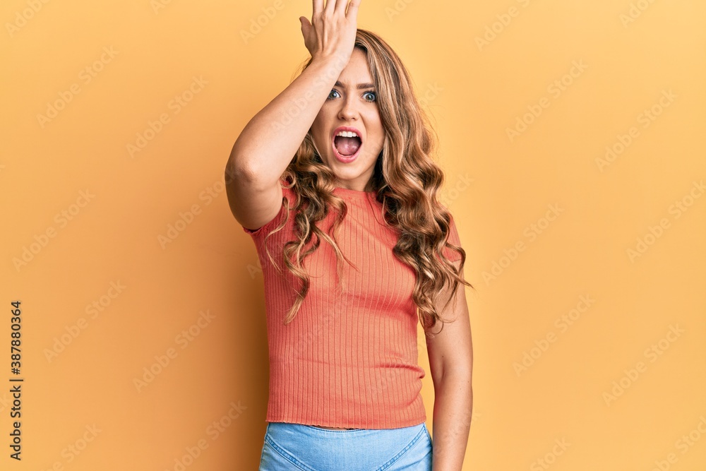 Young blonde girl wearing casual clothes surprised with hand on head for mistake, remember error. forgot, bad memory concept. Young blonde girl wearing casual clothes surprised with hand on head for mistake, remember error. forgot, bad memory concept.