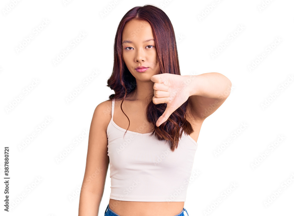 Young beautiful chinese girl wearing casual clothes looking unhappy and angry showing rejection and negative with thumbs down gesture. bad expression. Young beautiful chinese girl wearing casual clothes looking unhappy and angry showing rejection and negative with thumbs down gesture. bad expression.