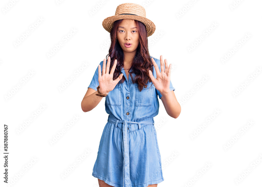 Young beautiful chinese girl wearing summer hat moving away hands palms showing refusal and denial with afraid and disgusting expression. stop and forbidden. Young beautiful chinese girl wearing summer hat moving away hands palms showing refusal and denial with afraid and disgusting expression. stop and forbidden.