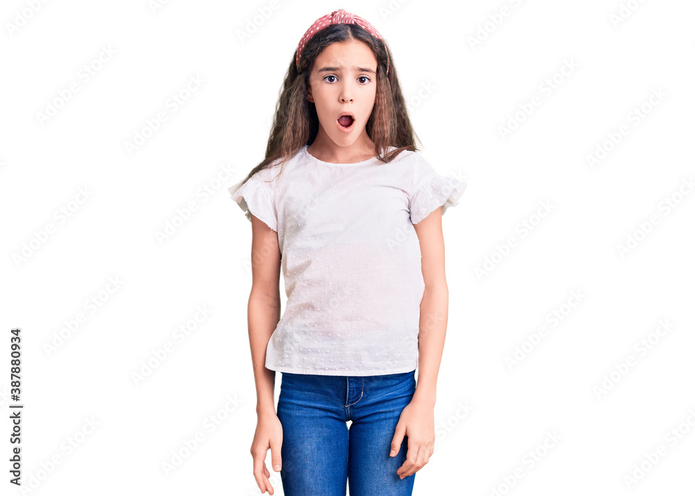 Cute hispanic child girl wearing casual white tshirt in shock face, looking skeptical and sarcastic, surprised with open mouth Cute hispanic child girl wearing casual white tshirt in shock face, looking skeptical and sarcastic, surprised with open mouth