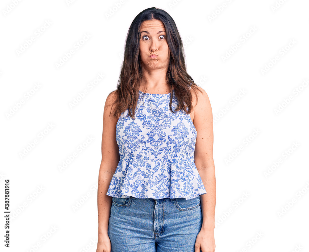 Obraz premium Young beautiful brunette woman wearing casual t-shirt puffing cheeks with funny face. mouth inflated with air, crazy expression.