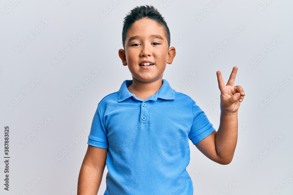Little boy hispanic kid wearing casual clothes smiling with happy face winking at the camera doing victory sign. number two. Little boy hispanic kid wearing casual clothes smiling with happy face winking at the camera doing victory sign. number two.