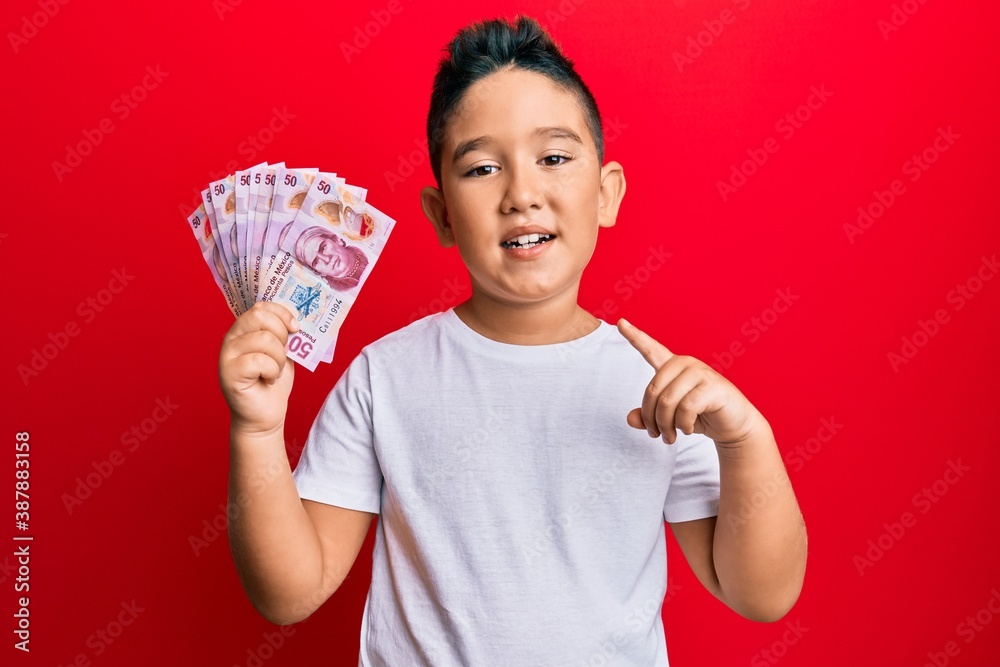 Little boy hispanic kid holding 50 mexican pesos banknotes smiling happy pointing with hand and finger Little boy hispanic kid holding 50 mexican pesos banknotes smiling happy pointing with hand and finger