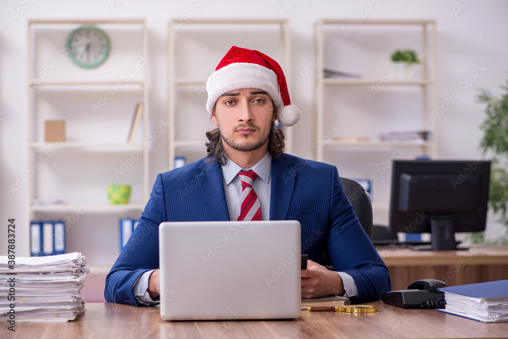 Young male employee working in the office at Christmas Eve Young male employee working in the office at Christmas Eve