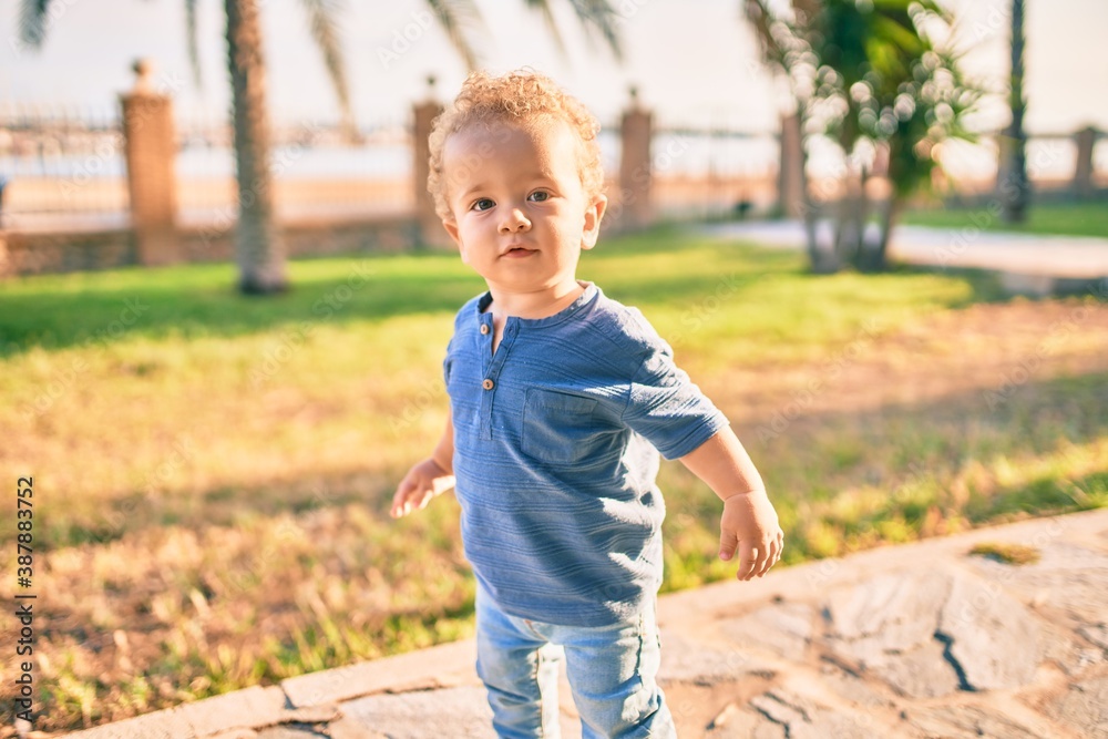 Cute and happy little boy having fun at the park on a sunny day. Beautiful blonde hair male toddler playing outdoors Cute and happy little boy having fun at the park on a sunny day. Beautiful blonde hair male toddler playing outdoors