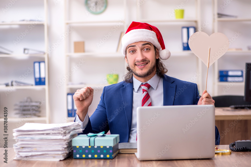 Young male employee working in the office at Christmas Eve Young male employee working in the office at Christmas Eve