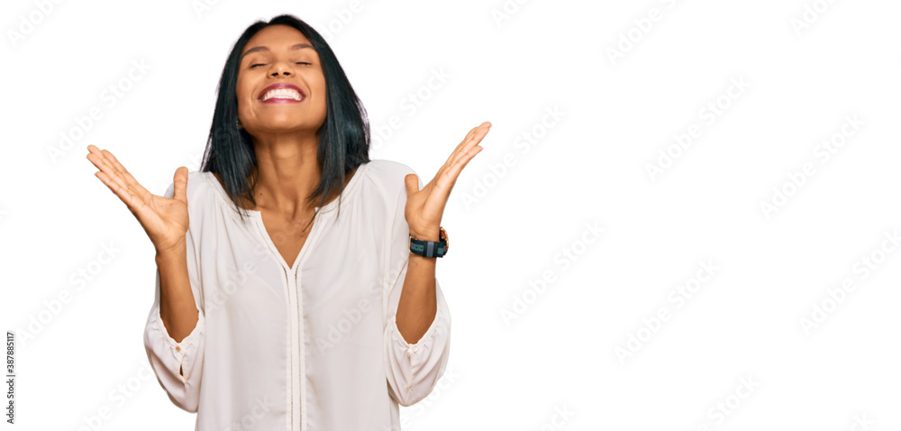 Young african american woman wearing casual clothes celebrating mad and crazy for success with arms raised and closed eyes screaming excited. winner concept Young african american woman wearing casual clothes celebrating mad and crazy for success with arms raised and closed eyes screaming excited. winner concept