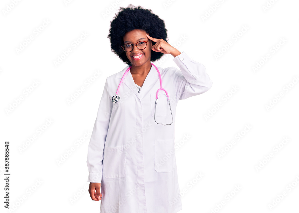 Young african american woman wearing doctor coat and stethoscope smiling pointing to head with one finger, great idea or thought, good memory