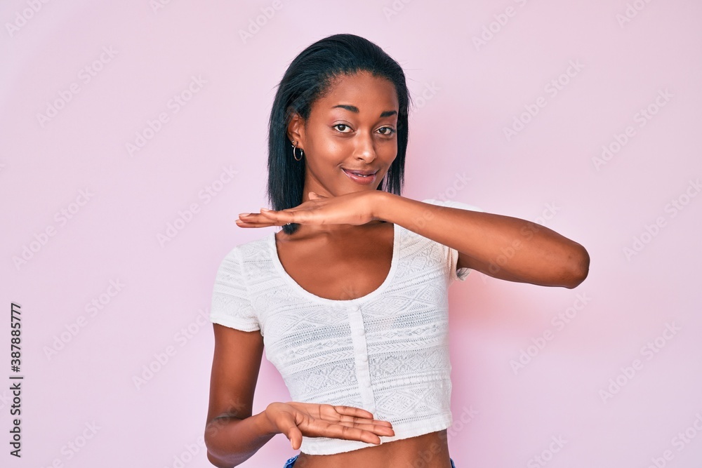 Young african american woman wearing casual clothes gesturing with hands showing big and large size sign, measure symbol. smiling looking at the camera. measuring concept. Young african american woman wearing casual clothes gesturing with hands showing big and large size sign, measure symbol. smiling looking at the camera. measuring concept.